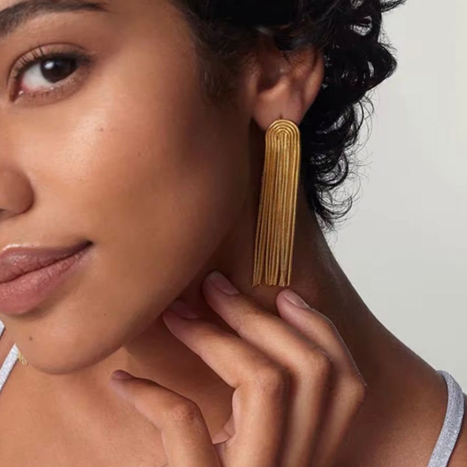 ujer usando pendientes de terracota con cabello recogido, sonriendo.